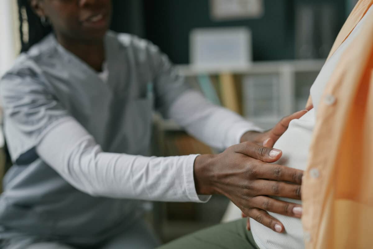 Young Adult Woman Receiving Prenatal Checkup from Black Female Doctor