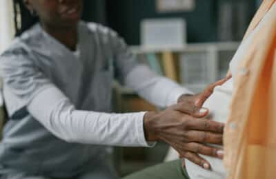 Young Adult Woman Receiving Prenatal Checkup from Black Female Doctor
