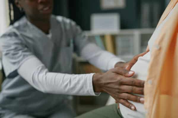 Young Adult Woman Receiving Prenatal Checkup from Black Female Doctor